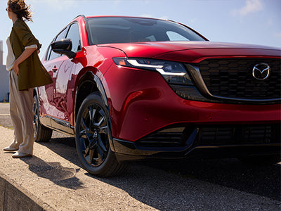 Red Mazda SUV with a person standing next to it on a sunny day.