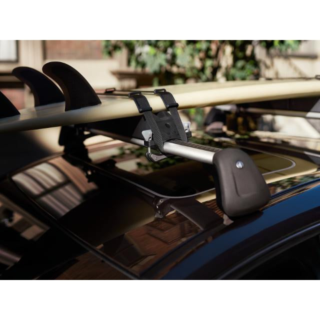 Surfboard attached to a car roof rack with a blurred background