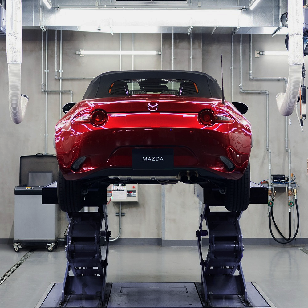 Red Mazda car on a lift in a garage